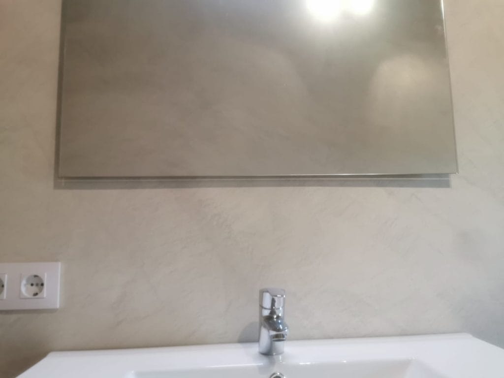 Detall del lavabo amb revestiment de microciment i mirall a Girona.