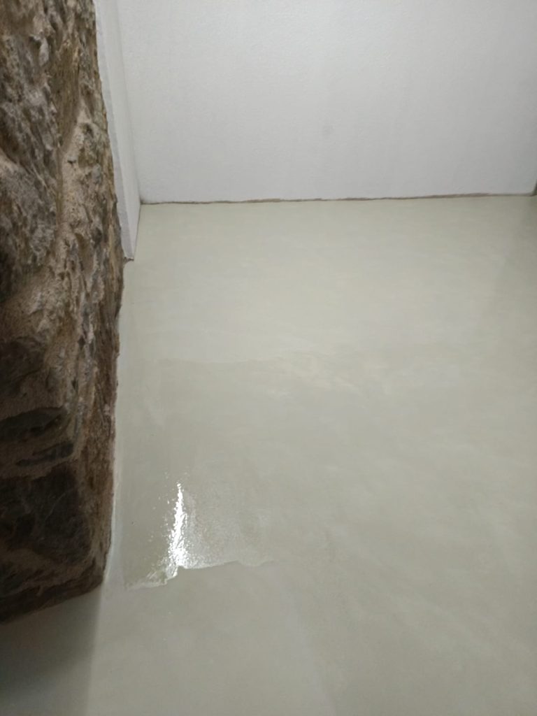 Sala amb parets de pedra i terra de microciment, combinació rústica i moderna.